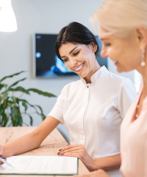 Smiling dental assistant showing patient forms