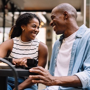 Couple smiling while enjoying cup of coffee outside