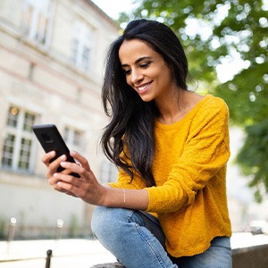 Woman smiling while looking at phone outside