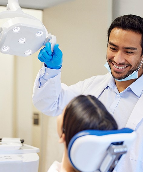 Dentist pulling light closer to examine patient’s mouth