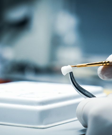 Gloved hands customizing dental crown