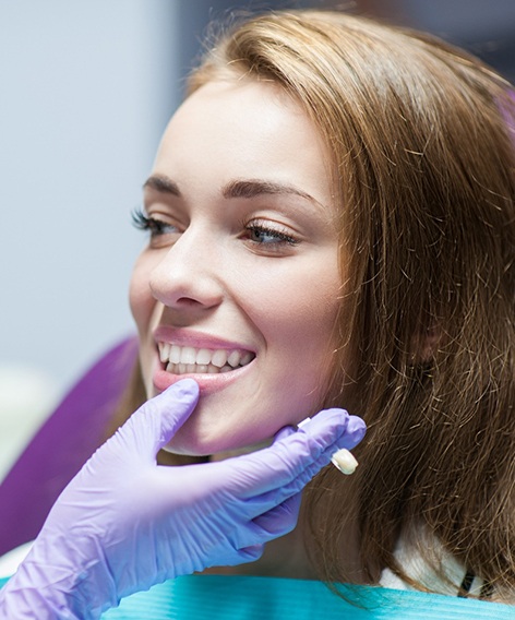 Purple-gloved hand touching dental patient’s chin and jaw
