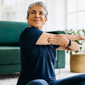 Senior woman smiling while stretching at home