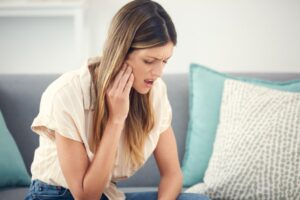 Woman holding side of face in pain. 