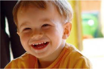 Child in yellow t-shirt smiling.